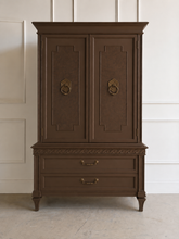 Load image into Gallery viewer, This vintage Mediterranean armoire has bold 1970s Spanish Revival styling with carved frieze detail, stepped door panels, burl veneer accents, and original brass ring hardware. The warm walnut-toned finish highlights the depth of the veneer, while the interior offers generous concealed storage with built-in drawers. Good Bones Furniture
