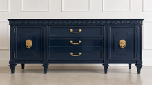 Load image into Gallery viewer, This vintage Mediterranean/ Spanish Revival credenza dresser has the scale, craftsmanship, and presence that make 1970s American case goods so collectible. The design features a carved scrolling frieze, burl veneer door panels, architectural legs, and original brass ring hardware with geometric backplates. Good Bones Furniture
