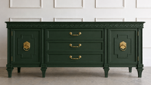 Load image into Gallery viewer, This vintage Mediterranean/ Spanish Revival credenza dresser has the scale, craftsmanship, and presence that make 1970s American case goods so collectible. The design features a carved scrolling frieze, burl veneer door panels, architectural legs, and original brass ring hardware with geometric backplates. Good Bones Furniture
