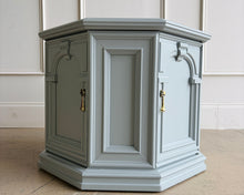 Load image into Gallery viewer, Professionally lacquered in Benjamin Moore Boothbay Gray, this vintage octagonal accent cabinet blends Hollywood Regency glamour with architectural neo-classical detailing. The octagonal silhouette, recessed panel molding, and arched faux-door styling give the piece strong boutique showroom presence. End table. Good Bones Furniture
