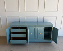 Load image into Gallery viewer, This vintage Stanley credenza clean lines, a flat rectangular top with crisp edges, and a solid plinth base that grounds the piece visually. Five doors open to three interior cabinet sections, giving you flexible storage for dining, media, or everyday living. The far-left section includes three draw
