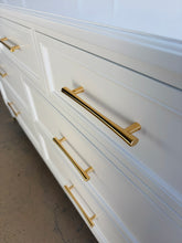 Load image into Gallery viewer, This vintage dresser by Kindel Furniture blends heirloom craftsmanship with a fresh, tailored update. Professionally lacquered in Benjamin Moore White Dove, the finish gives the piece a soft, warm white presence that feels crisp without feeling stark. Fluted corner posts add subtle classical detail, while slim brass bar pulls and brass-capped feet introduce a refined modern contrast. Good Bones Furniture
