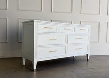 Load image into Gallery viewer, This vintage dresser by Kindel Furniture blends heirloom craftsmanship with a fresh, tailored update. Professionally lacquered in Benjamin Moore White Dove, the finish gives the piece a soft, warm white presence that feels crisp without feeling stark. Fluted corner posts add subtle classical detail, while slim brass bar pulls and brass-capped feet introduce a refined modern contrast. Good Bones Furniture
