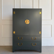 Load image into Gallery viewer, The White Furniture Co. Chin Hua Armoire is an iconic statement piece with a clean, architectural silhouette and unmistakable campaign-inspired details. Finished in Farrow &amp; Ball Studio Green, this piece brings dramatic, saturated color to the classic Chin Hua design language—sharp lines, recessed panel doors, and bold brass accents that feel timeless rather than trendy. Use it as a wardrobe, bar cabinet, or elevated storage anywhere you want a true focal point.
