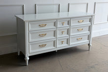 Load image into Gallery viewer, This vintage 7 drawer dresser by White Furniture Co. pairs quality construction with a clean, updated finish. Lacquered in Benjamin Moore White Dove, the soft creamy white highlights the layered drawer molding and tapered turned legs. The original hardware has been painted gold. Good Bones Furniture
