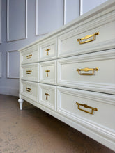 Load image into Gallery viewer, This vintage 7 drawer dresser by White Furniture Co. pairs quality construction with a clean, updated finish. Lacquered in Benjamin Moore White Dove, the soft creamy white highlights the layered drawer molding and tapered turned legs. The original hardware has been painted gold. Good Bones Furniture
