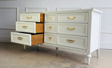 Load image into Gallery viewer, This vintage 7 drawer dresser by White Furniture Co. pairs quality construction with a clean, updated finish. Lacquered in Benjamin Moore White Dove, the soft creamy white highlights the layered drawer molding and tapered turned legs. The original hardware has been painted gold. Good Bones Furniture
