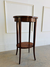 Load image into Gallery viewer, This elegant Wildwood accent table draws heavily from classic Federal and Regency design, featuring an oval silhouette, tapered saber legs, and richly patterned mahogany veneers inspired by fine English antiques. The proportions feel graceful and architectural, while the warm finish and decorative inlay work give the piece exceptional depth and character. Good Bones Furniture
