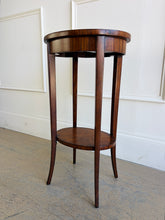 Load image into Gallery viewer, This elegant Wildwood accent table draws heavily from classic Federal and Regency design, featuring an oval silhouette, tapered saber legs, and richly patterned mahogany veneers inspired by fine English antiques. The proportions feel graceful and architectural, while the warm finish and decorative inlay work give the piece exceptional depth and character. Good Bones Furniture
