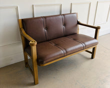 Load image into Gallery viewer, The Woodbridge Furniture Hayes Settee is a handsome interpretation of an early 20th-century Arts and Crafts station bench, blending heritage inspiration with clean, enduring lines. A solid hardwood frame in the Auden finish surrounds a richly upholstered brown leather back and seat, creating a balanced contrast between warm wood tones and supple leather. Good Bones Furniture
