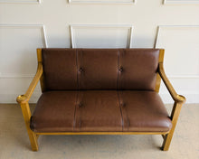 Load image into Gallery viewer, Squared posts, broad arms, and structured proportions give the piece architectural presence, while the tailored leather upholstery adds comfort and refinement. The result is a settee that feels grounded, timeless, and quietly sophisticated—equally suited for an entryway, office, living room, or at the foot of a bed.
