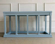 Load image into Gallery viewer, Neoclassical console table finished in Farrow &amp; Ball Parma Gray, shown straight on with fluted legs and a plinth-style base against a white paneled wall.
