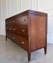 Load image into Gallery viewer, Low angled left view of the Theodore Alexander Dorchester Dresser highlighting tapered legs, stepped architectural lines, and richly figured walnut veneer, photographed at Good Bones Furniture in Raleigh, North Carolina.
