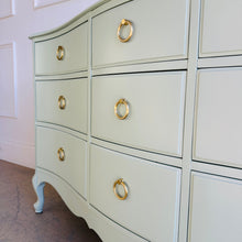 Load image into Gallery viewer, Close-up of brass ring pull hardware on a vintage French dresser with a painted green finish.
